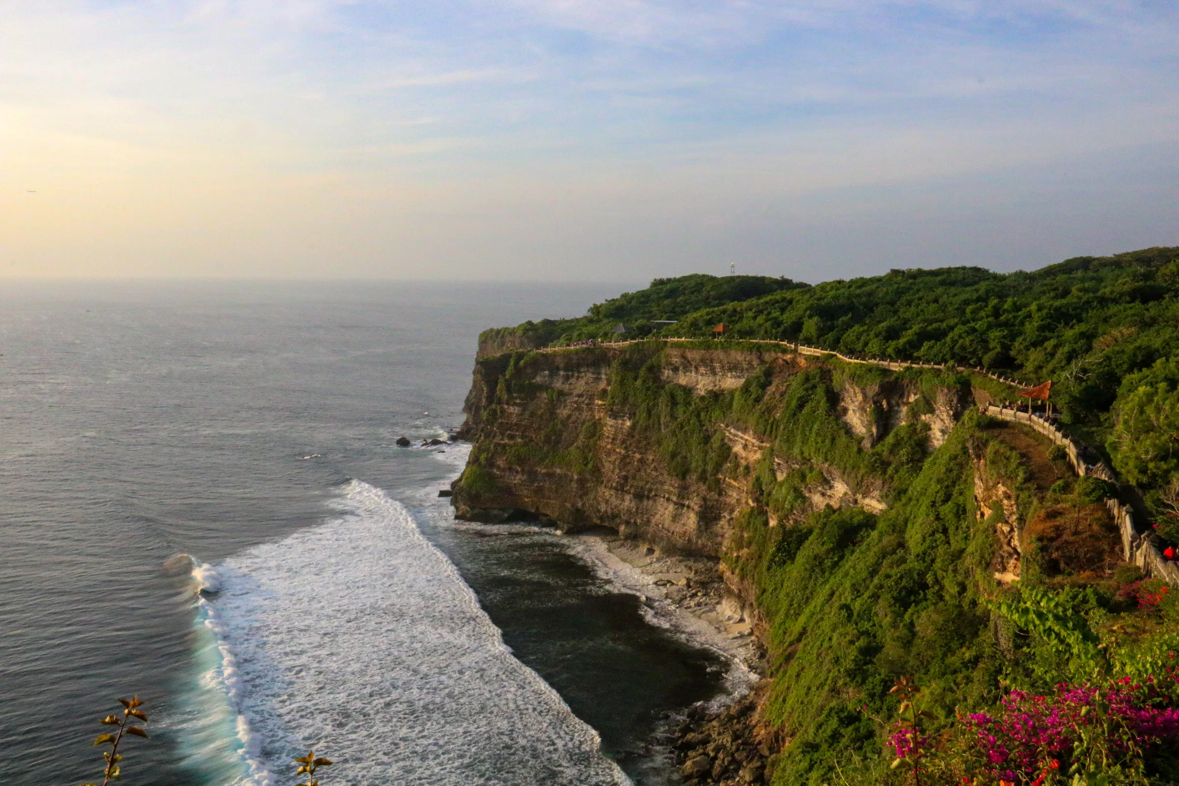 Green limestone cliffs dropping into white surf, seen from Uluwatu Temple