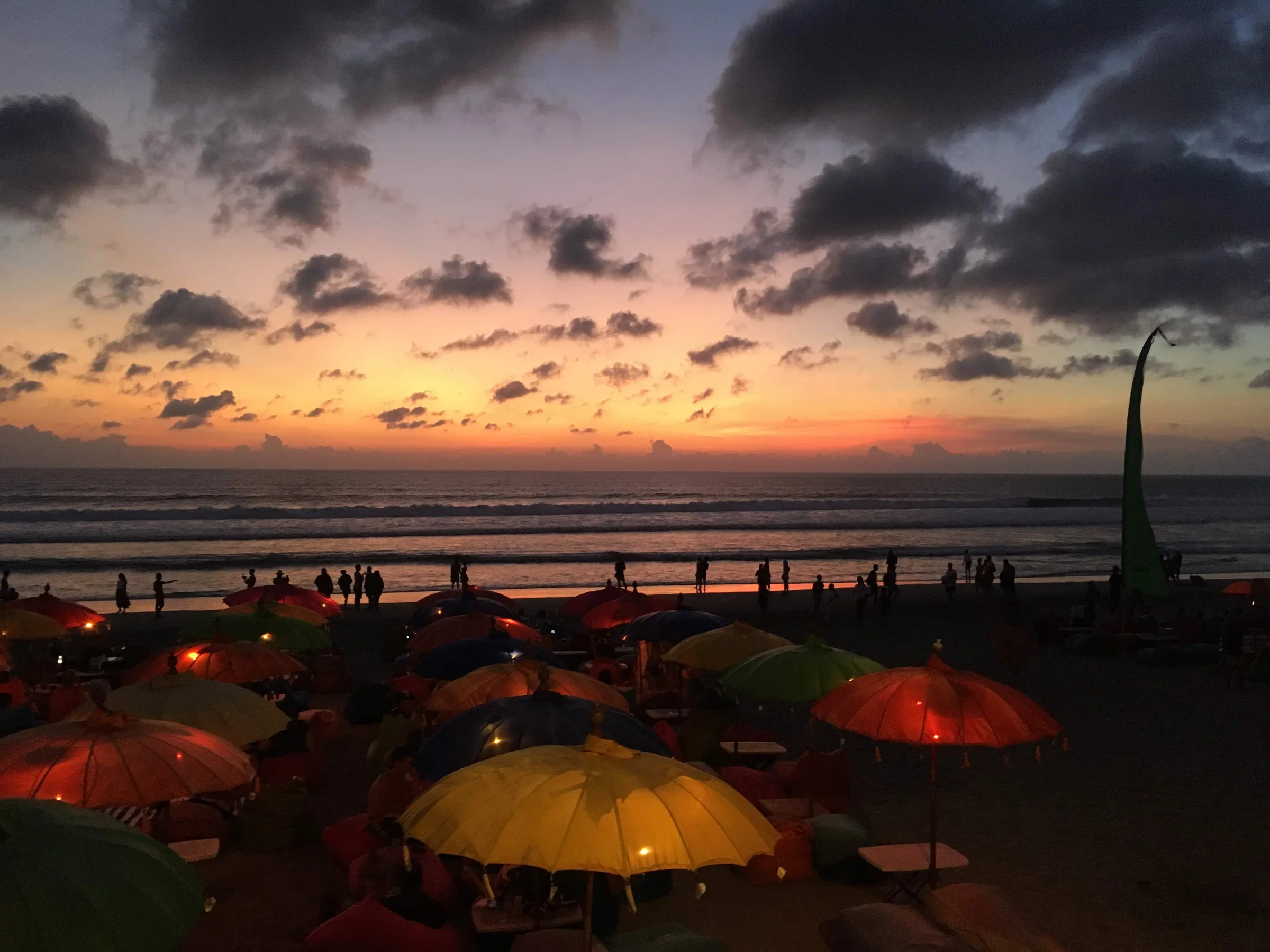 Coloured umbrellas on Seminyak Beach under a dramatic sunset sky