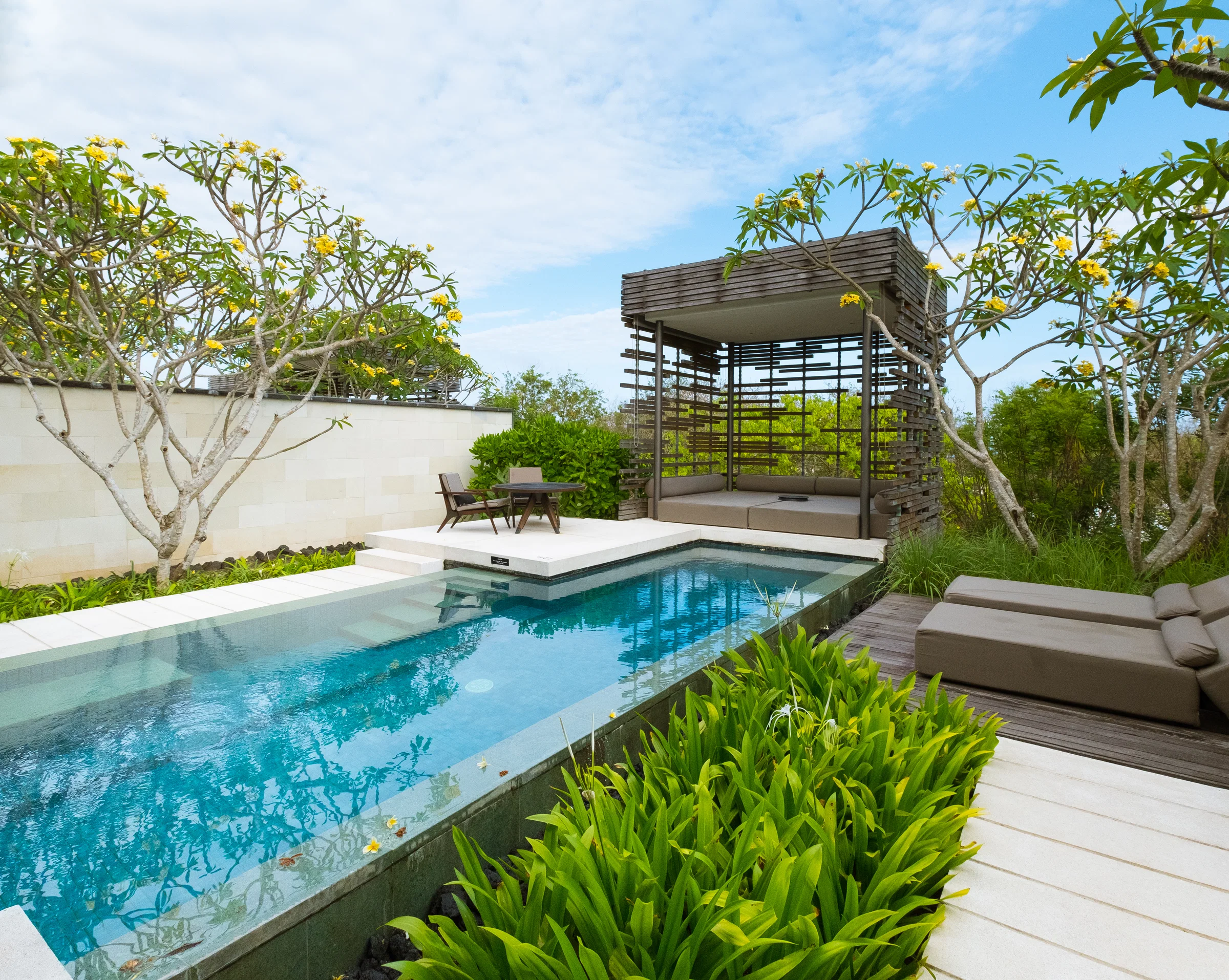 A private villa pool with a shaded pavilion and frangipani trees at Alila Villas, Bali