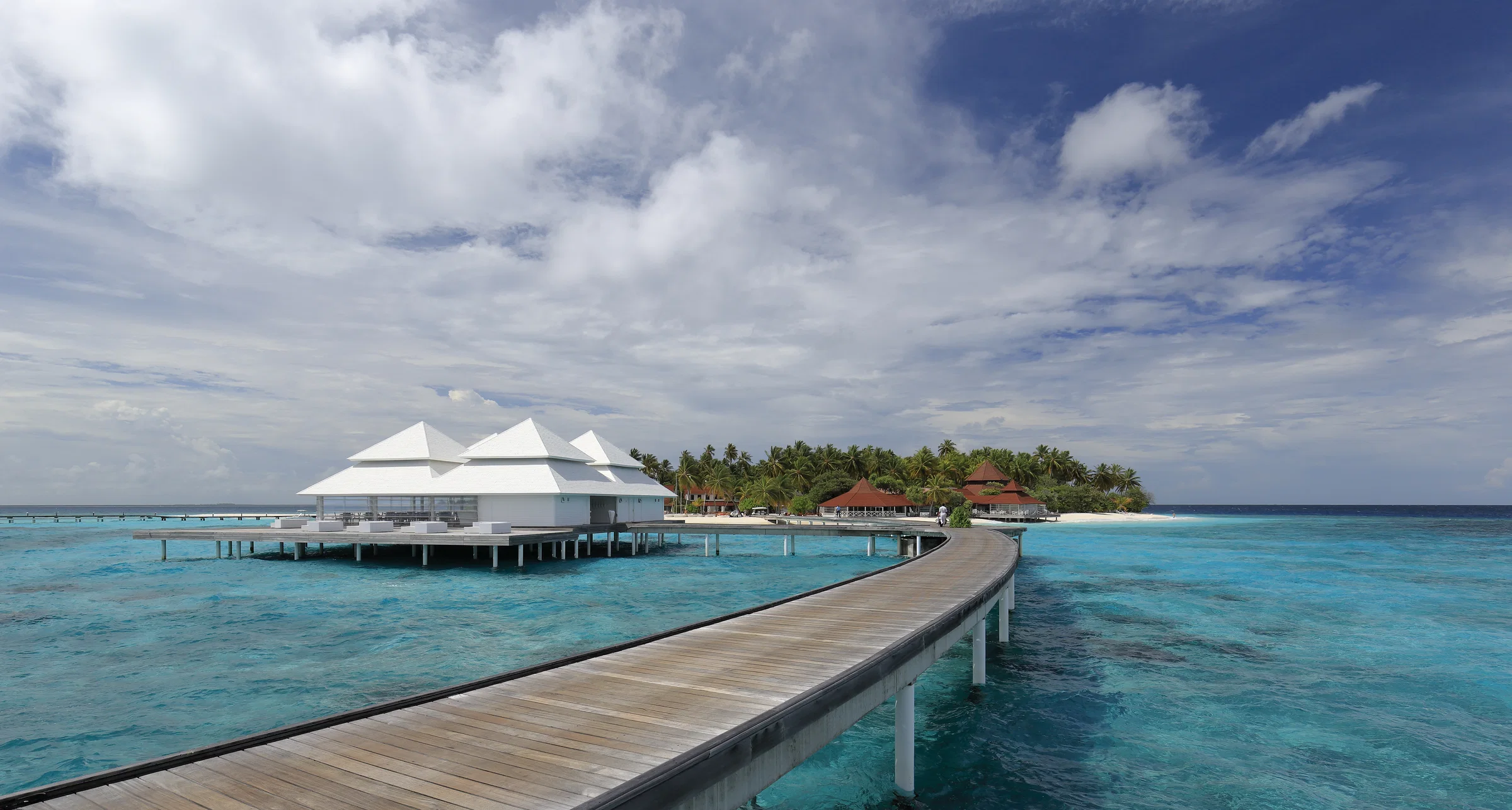 A wooden jetty leading to overwater villas on a turquoise lagoon, Thudufushi, Ari Atoll