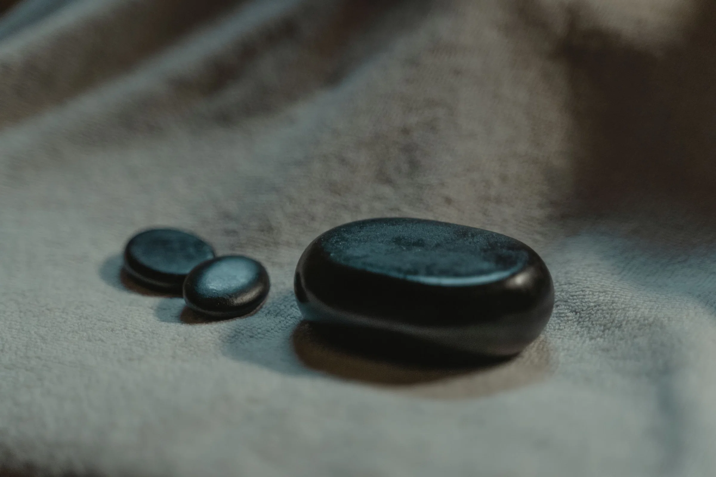Smooth black massage stones on a soft towel