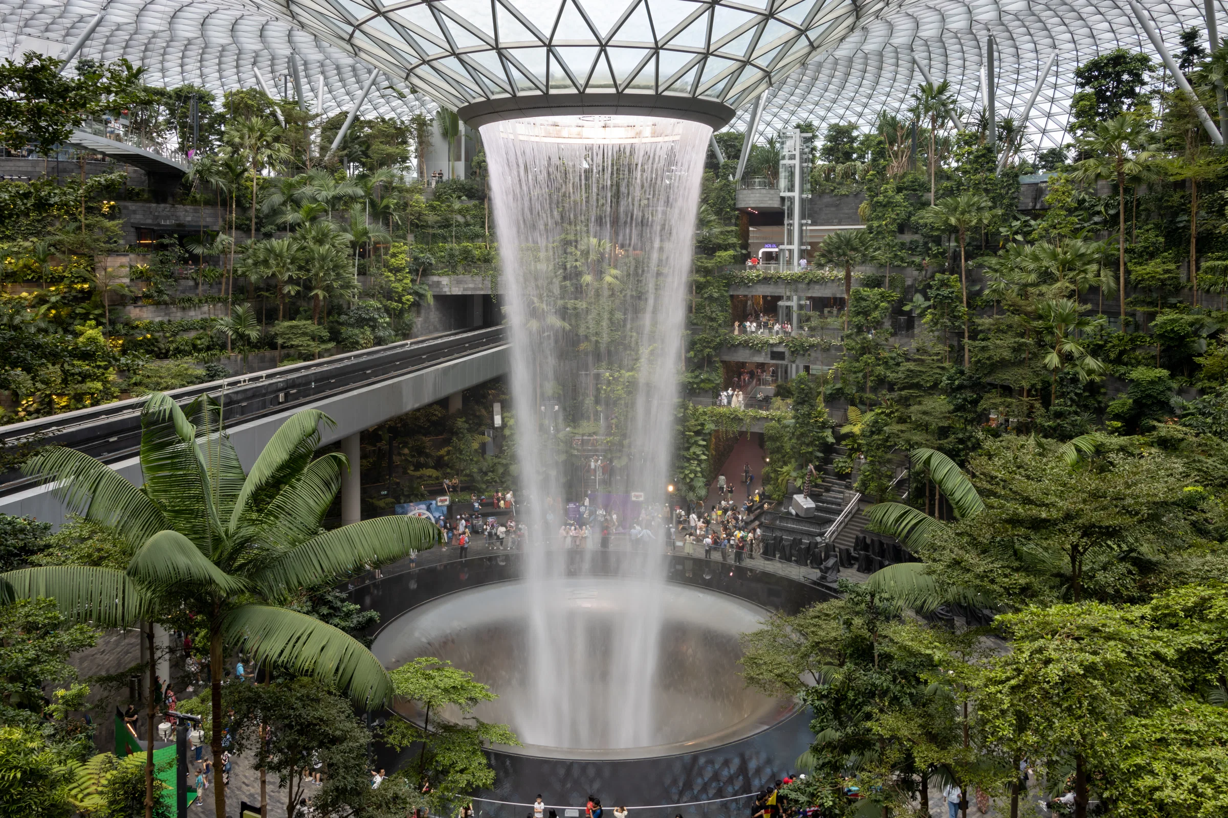 The Rain Vortex falling through the glass dome of Jewel Changi Airport into the planted Forest Valley