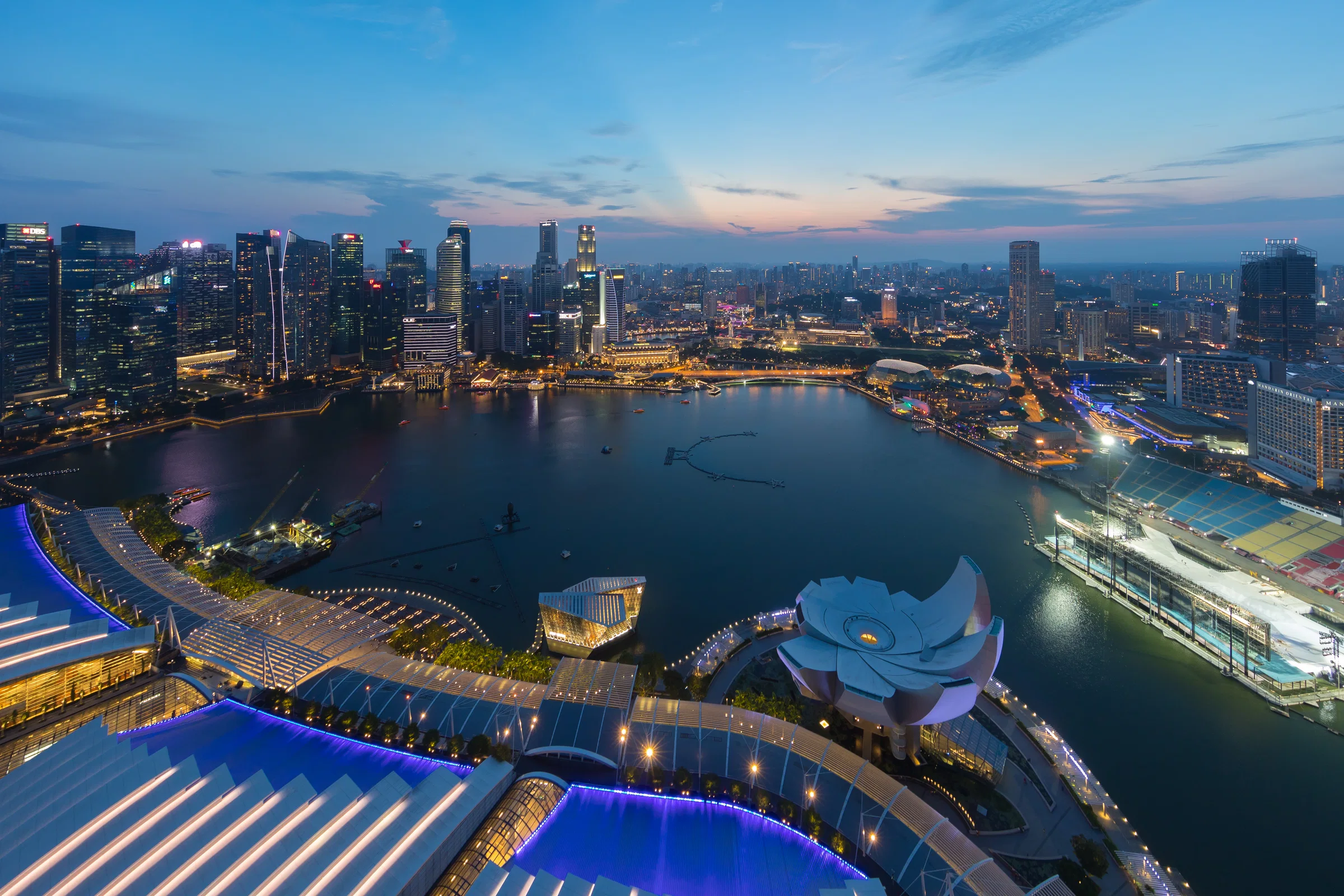 Marina Bay and the city skyline at dusk, seen from the Marina Bay Sands observation deck, with the ArtScience Museum below