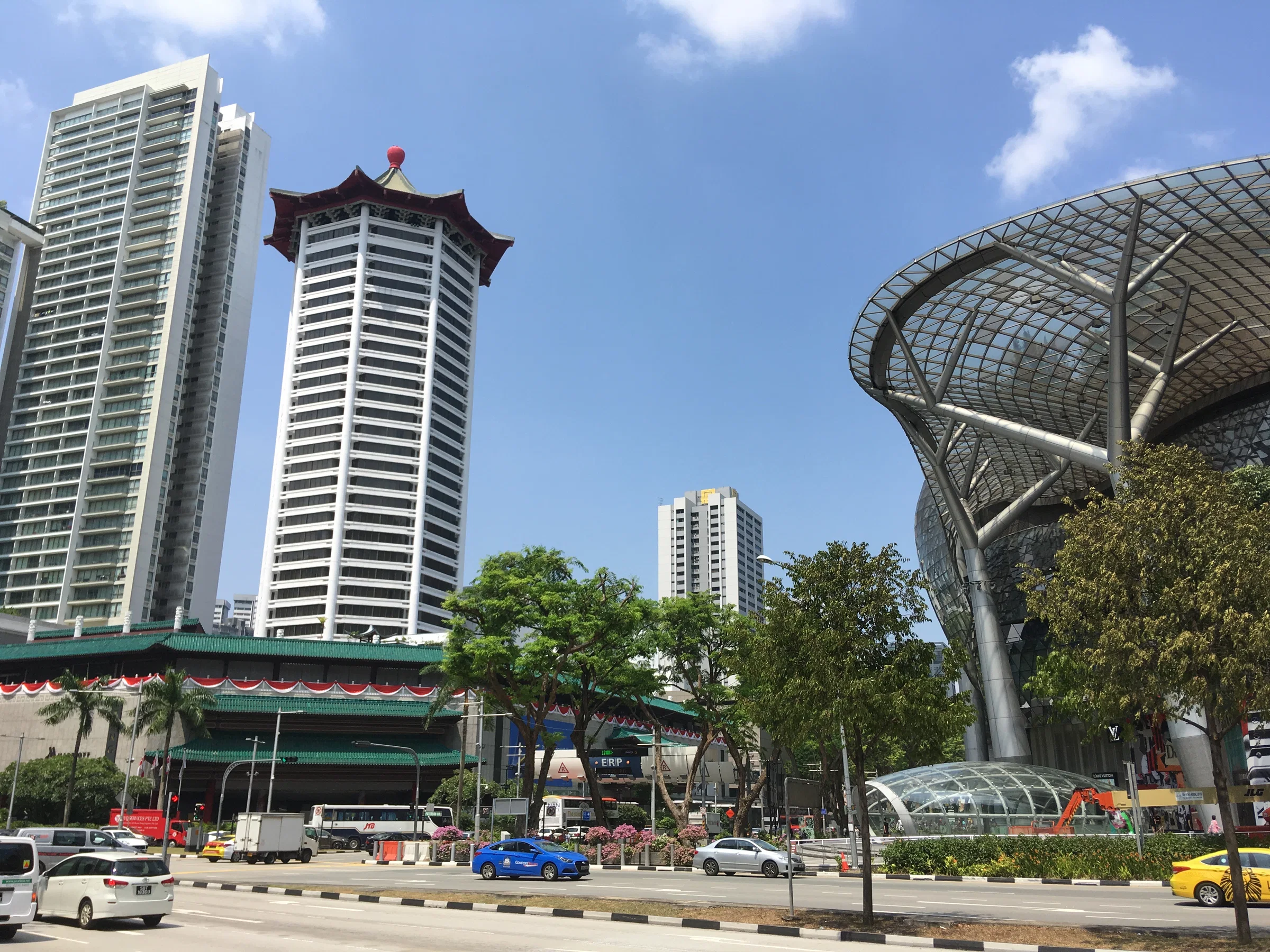 Orchard Road on a sunny day, with the curved canopy of ION Orchard and the pagoda-roofed towers across the street