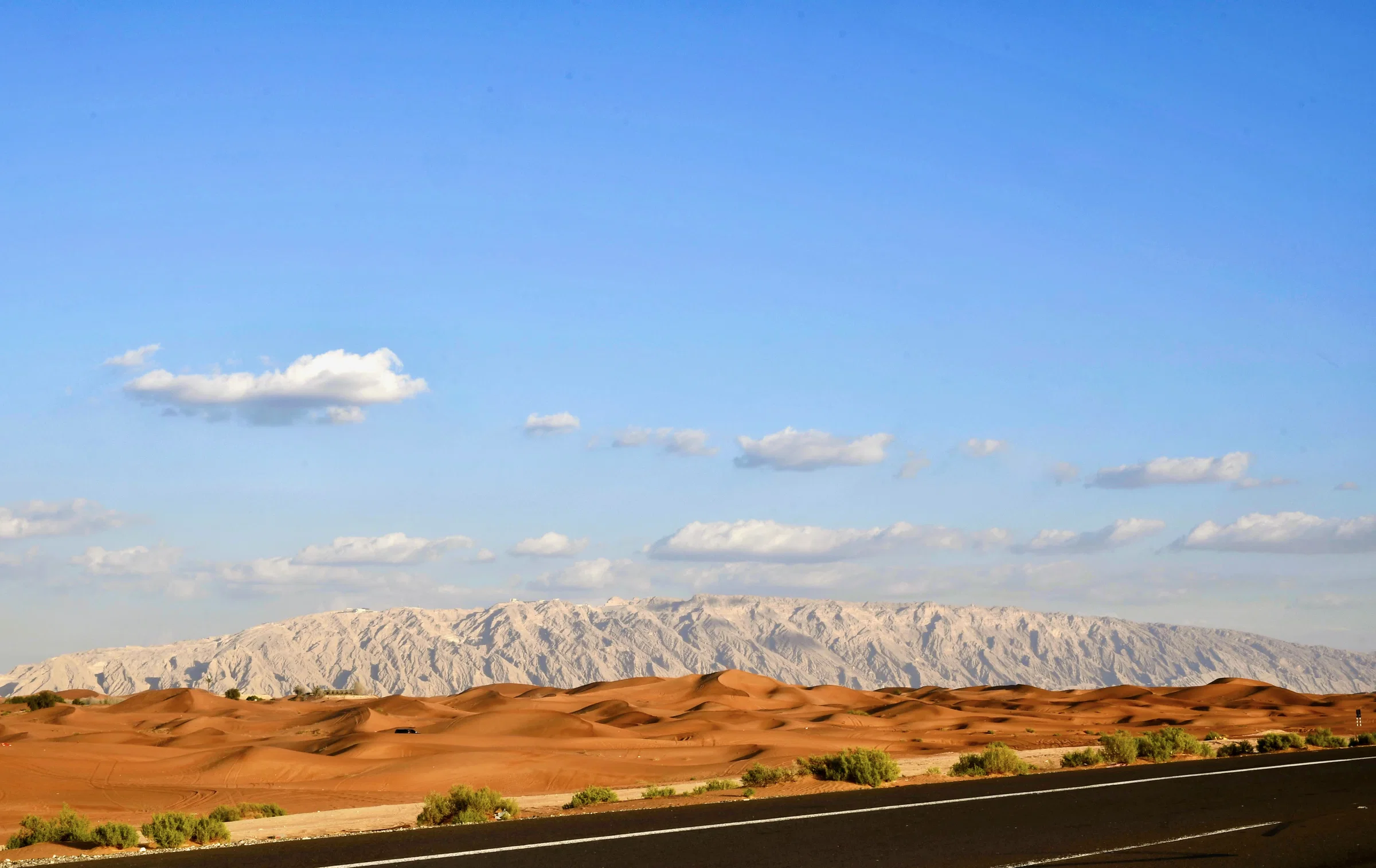 Jebel Hafeet rising behind red sand dunes near Al Ain