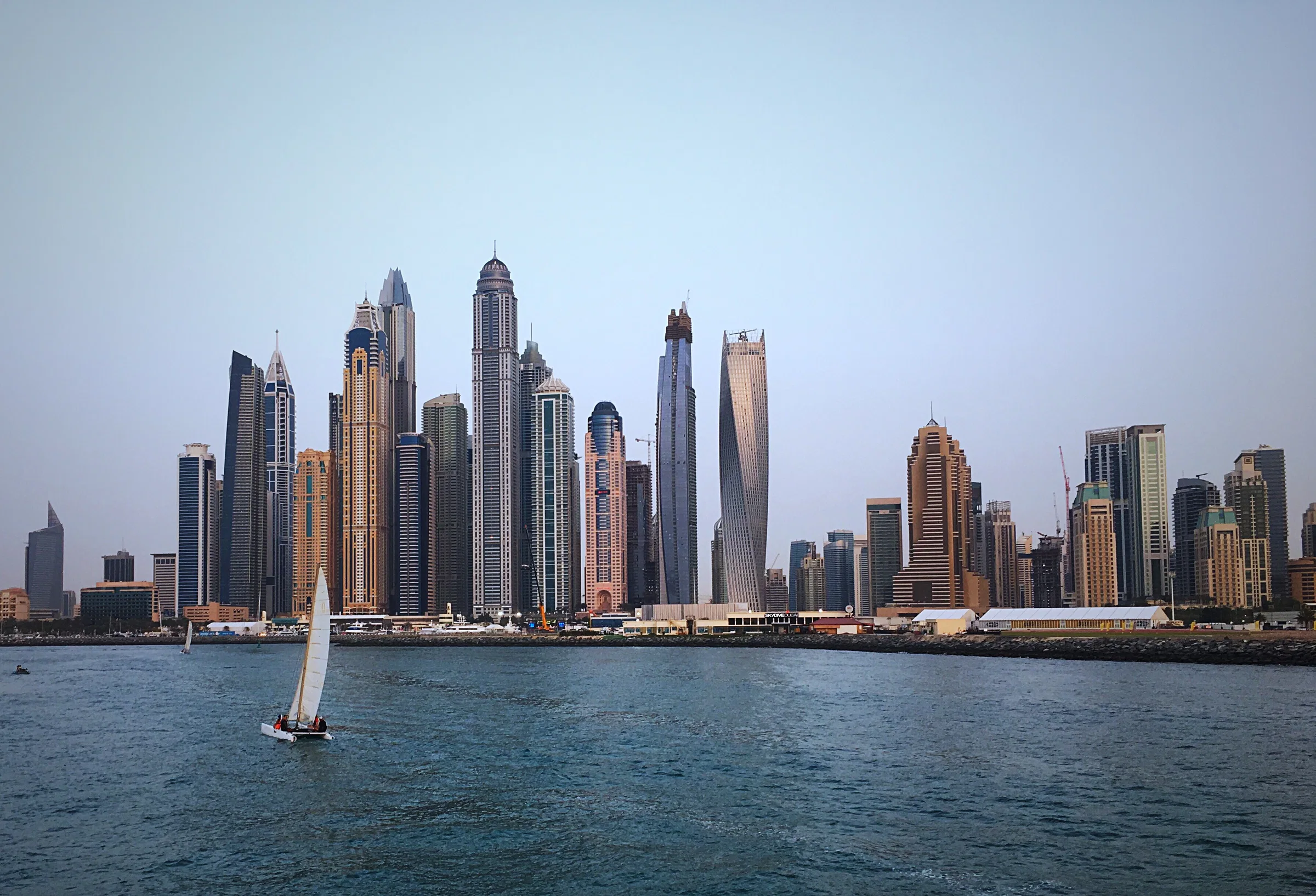 قارب شراعي أمام أبراج دبي مارينا، كما يبدو من يخت
