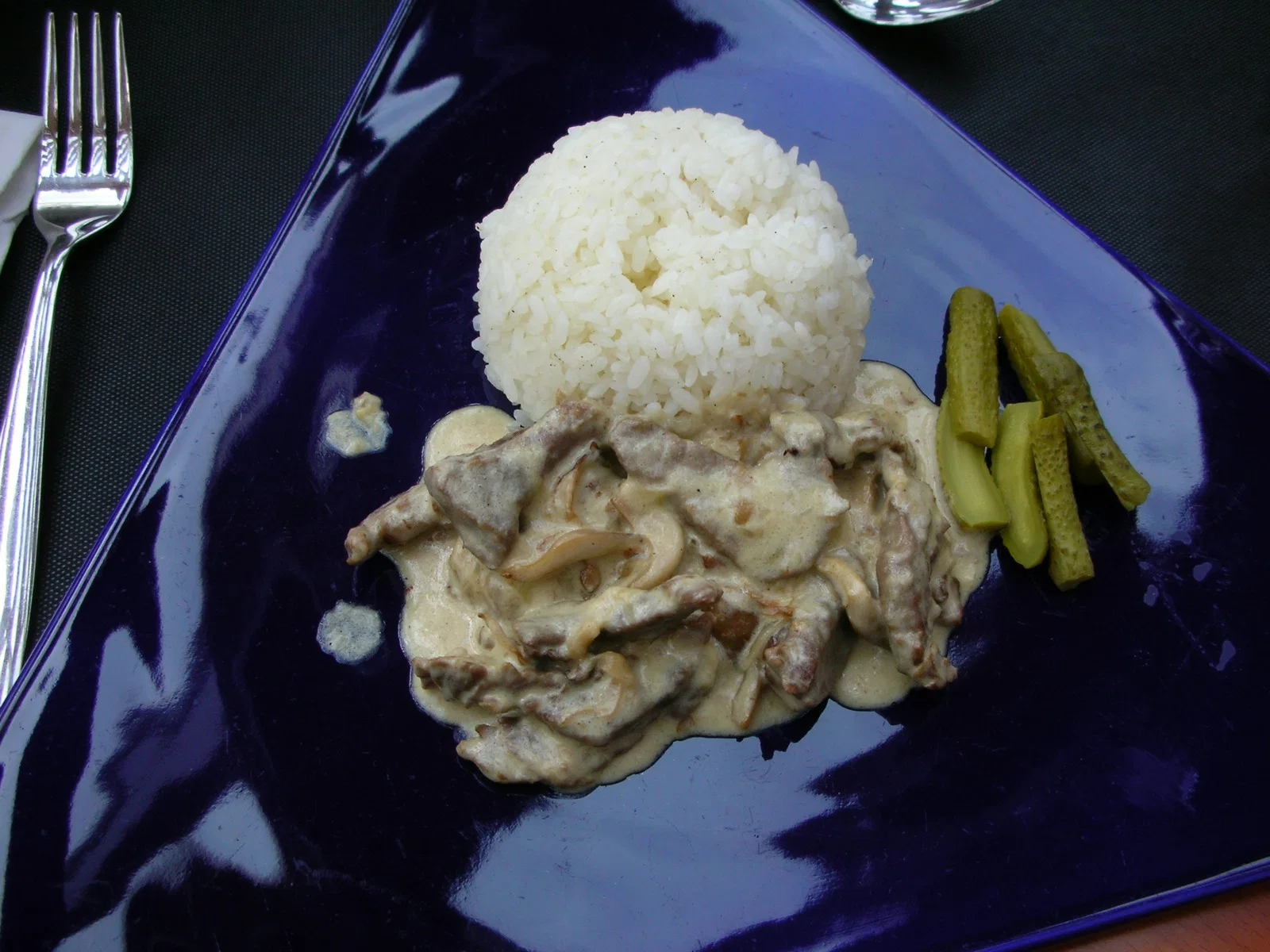 Beef stroganoff in a creamy sauce with rice and pickled cucumbers, served in Moscow