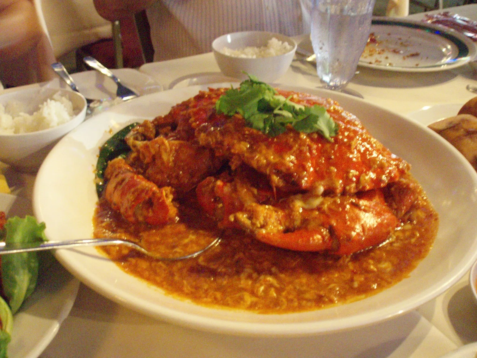 Chilli crab in a thick red tomato and chilli sauce, served on a white plate in Singapore