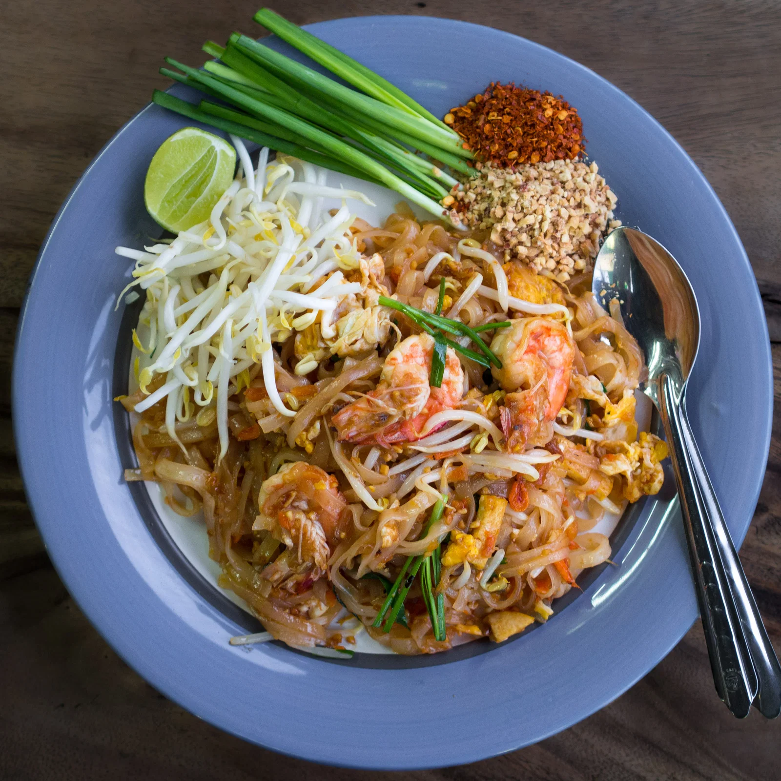 A plate of prawn pad Thai with lime and spring onion from a Chiang Mai street stall